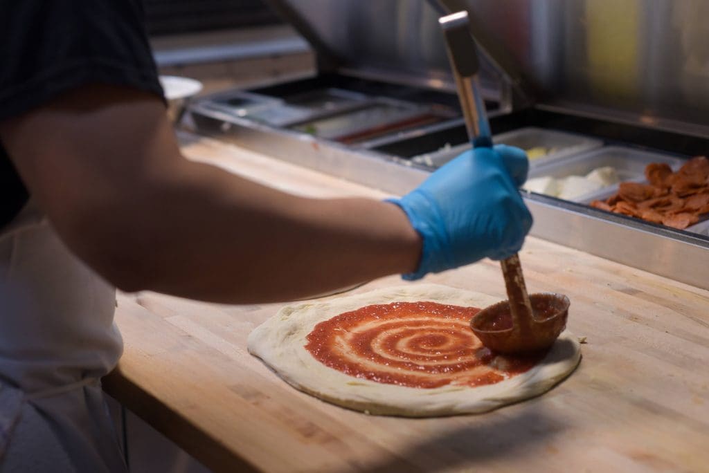 putting sauce on a pizza brick + dough