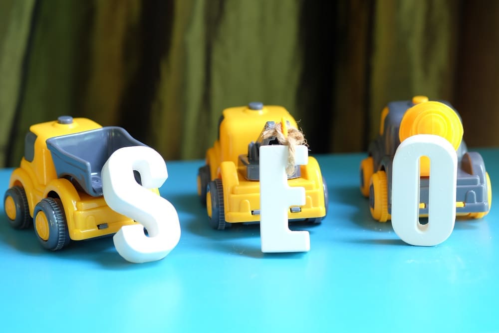 Three toy cars arranging a word SEO out of white letters