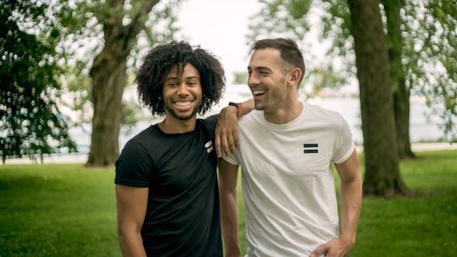 Two men standing on the grass and smiling