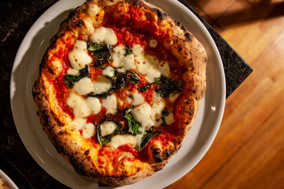 A Margherita pizza from Aquila Pizza Al Forno in Little Falls, NJ, featuring handmade mozzarella, San Marzano tomatoes, and fresh basil on a wood-fired crust with charred cornicione.