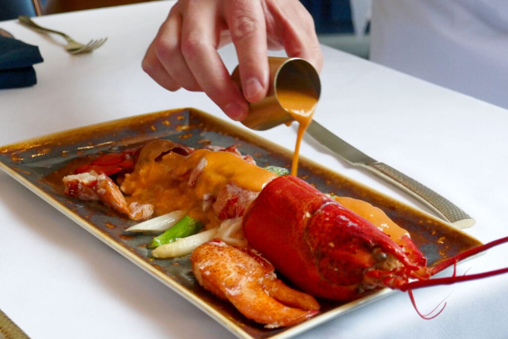 A deconstructed lobster is reassembled and sauced tableside