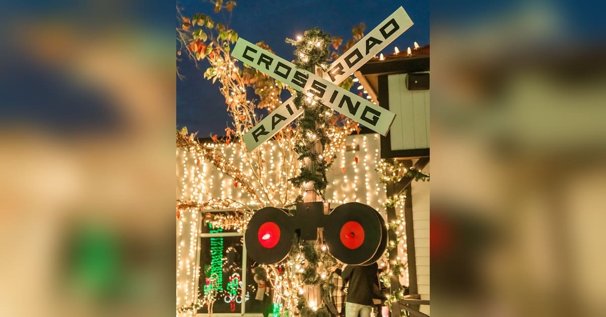 Railroad crossing signal wrapped in holiday lights at DiDonato’s Christmas train attraction in Hammonton, NJ.