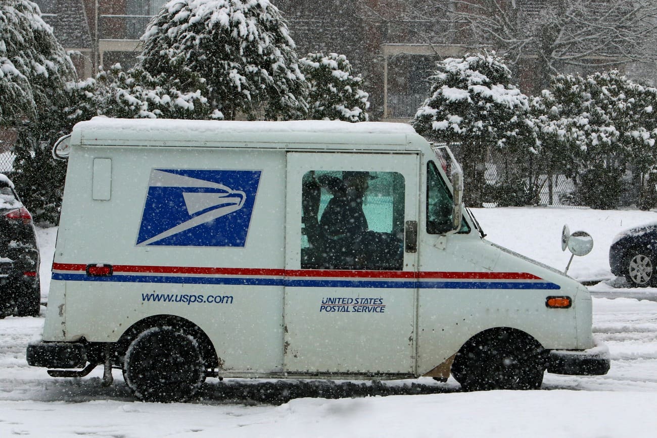 Mail truck delivering holiday parcels on a snow-covered street