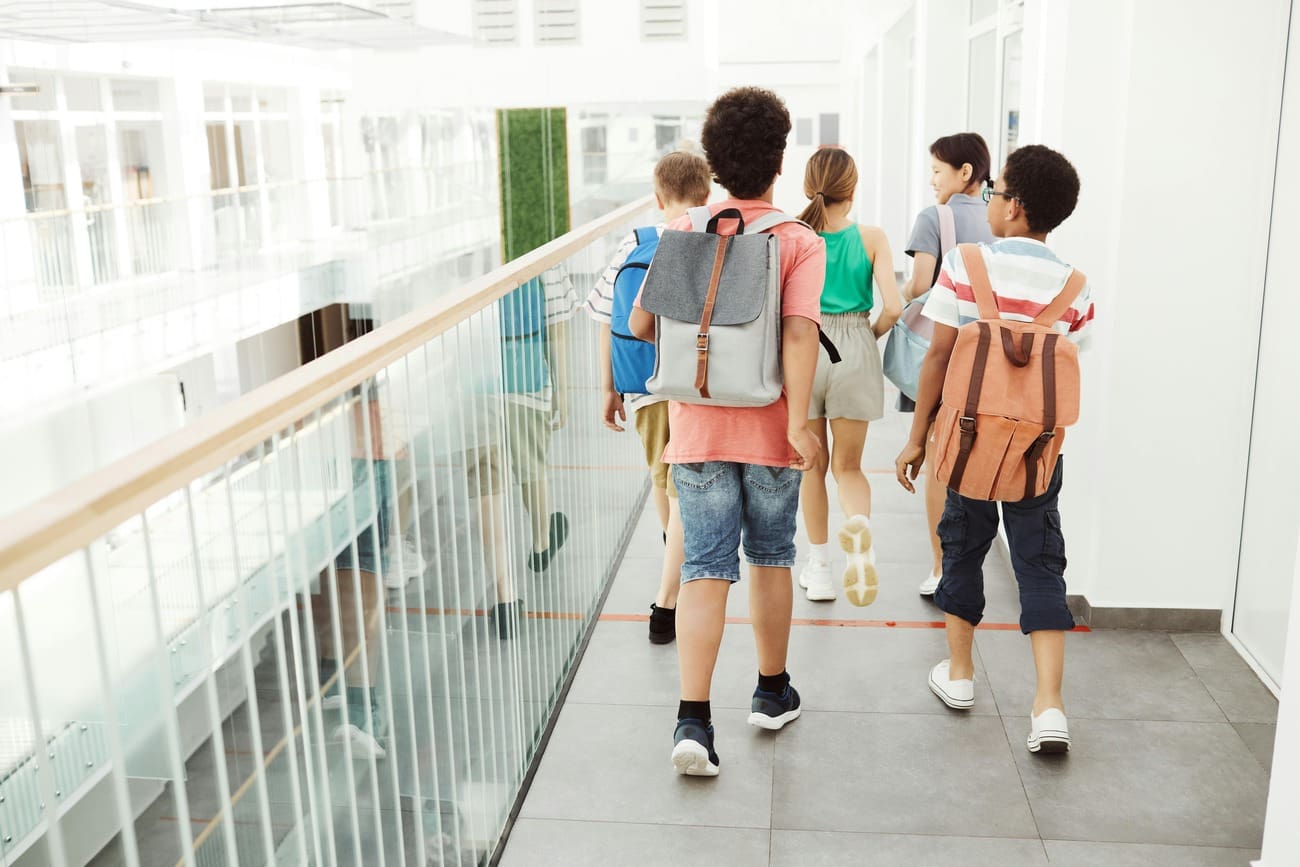 Middle school students walk and talk in a bright school hallway