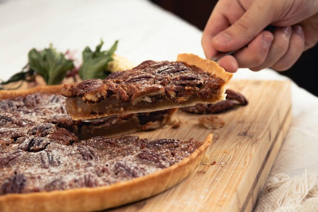 A Hand Holding a Slice of Pecan Pie