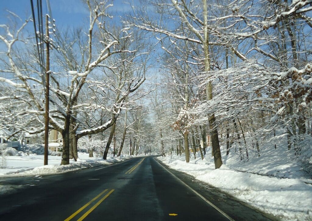 Snow-covered street lined with trees and homes in Summit, New Jersey on a winter day.