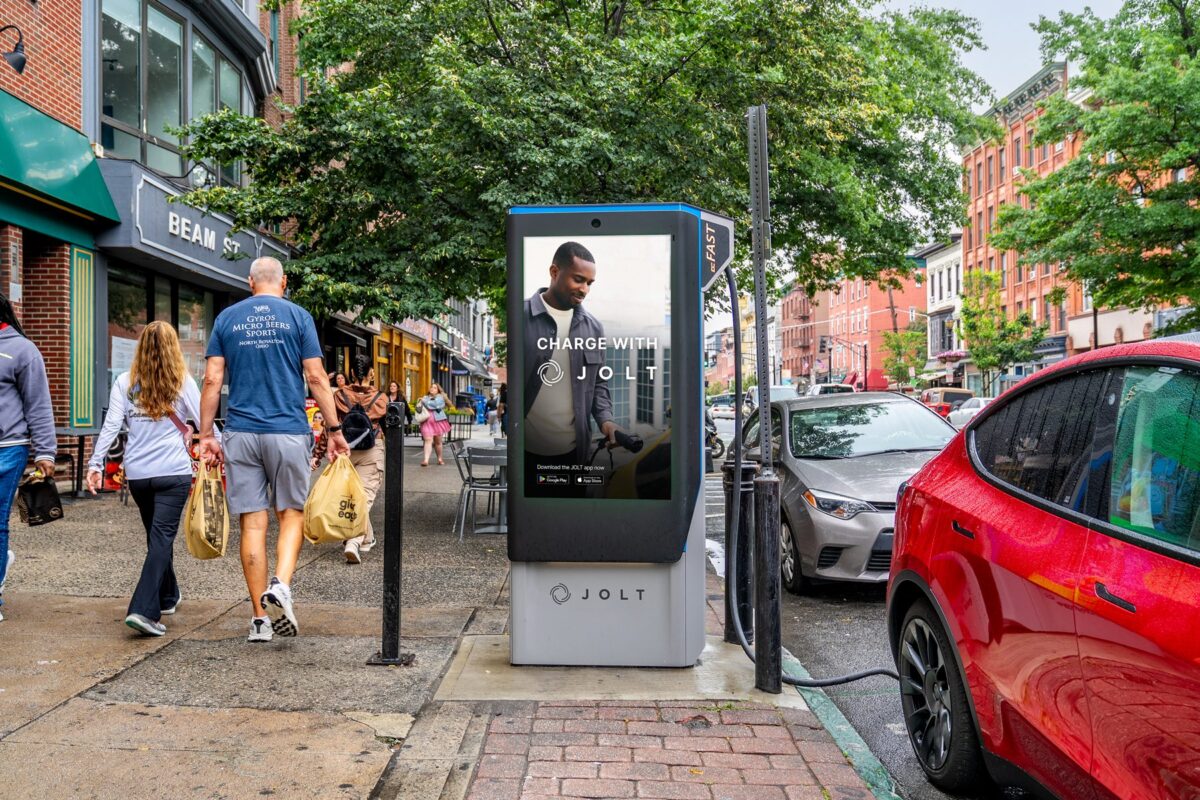 OLT electric vehicle charging station on Hoboken street with integrated advertising screen, showing how the ad-funded model supports municipal EV infrastructure