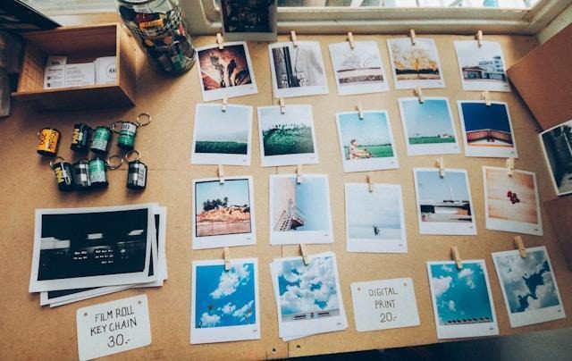 An assortment of physical Polaroid photos on a board, next to film rolls and other photos.