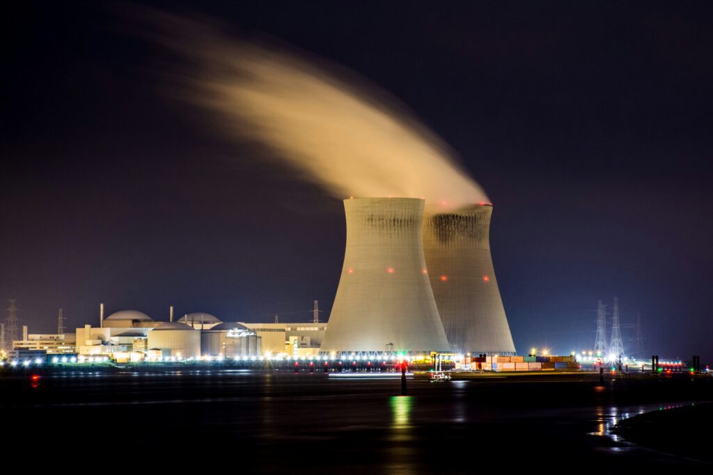 Nuclear power plant with cooling towers illuminated at night, as New Jersey Assembly advances bill A4528 to expand nuclear energy in the state