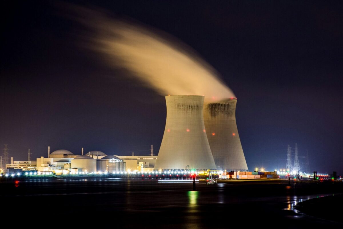 Nuclear power plant with cooling towers illuminated at night, as New Jersey Assembly advances bill A4528 to expand nuclear energy in the state