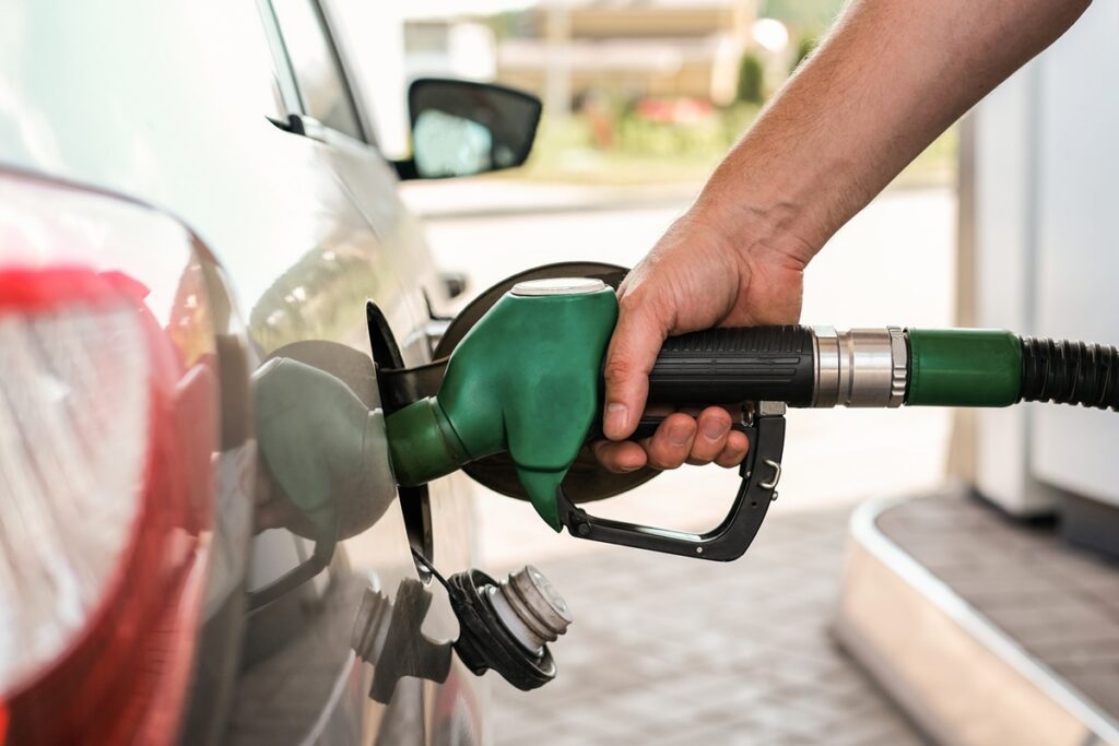 Driver refueling a car at a gas station as fuel prices rise