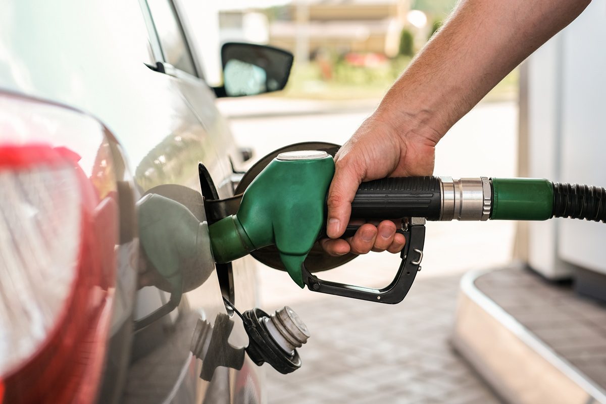 Driver refueling a car at a gas station as fuel prices rise
