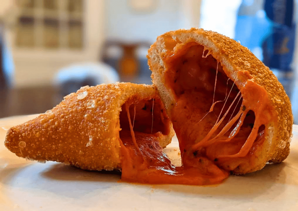 A panzarotti split open showing melted mozzarella cheese and tomato sauce