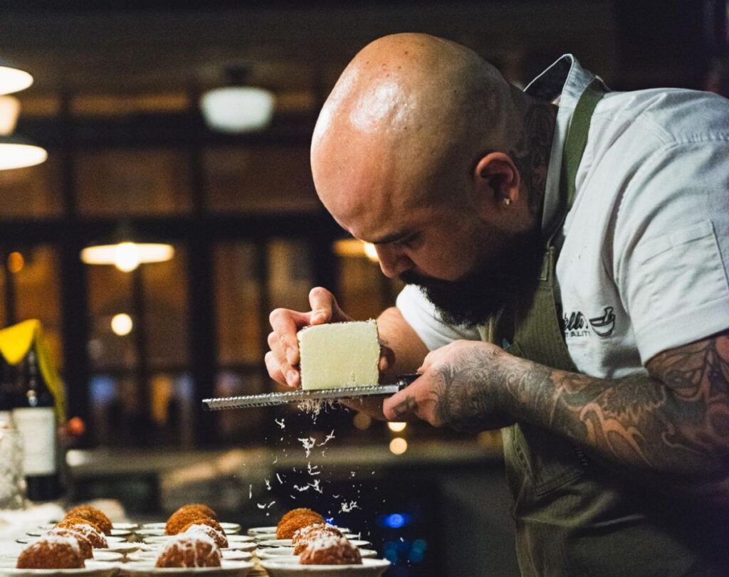 chef bryan giron grates cheese on a dish