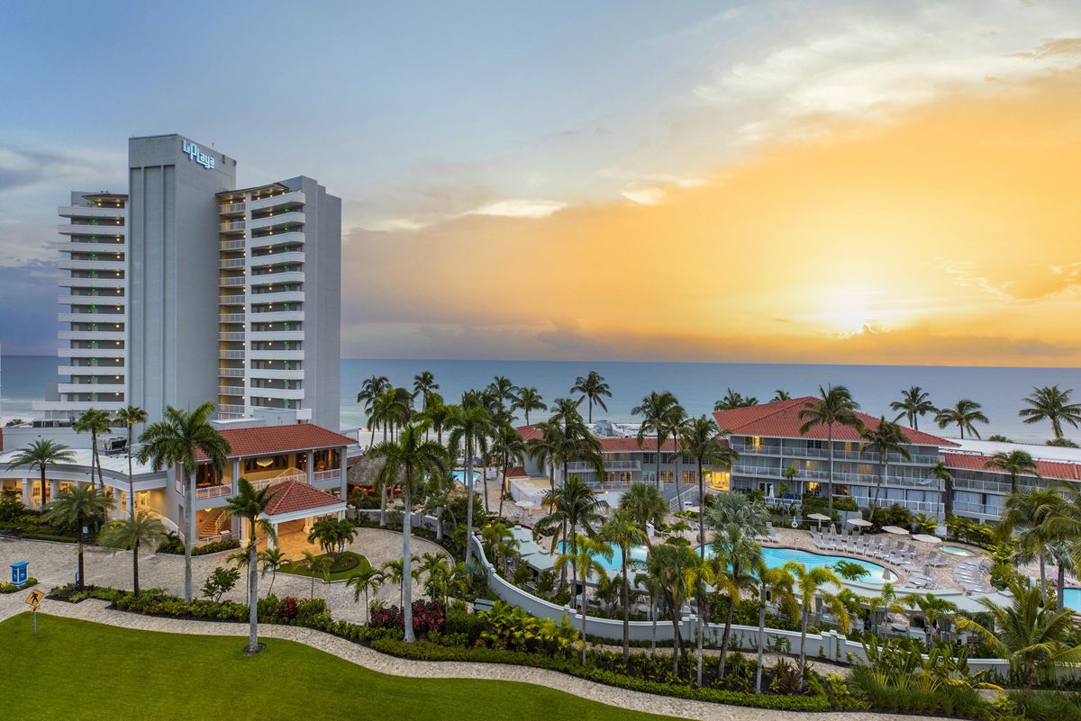 Aerial sunset view of La Playa Beach and Golf Resort in Naples, Florida, showing the resort tower, pools, and Gulf of Mexico