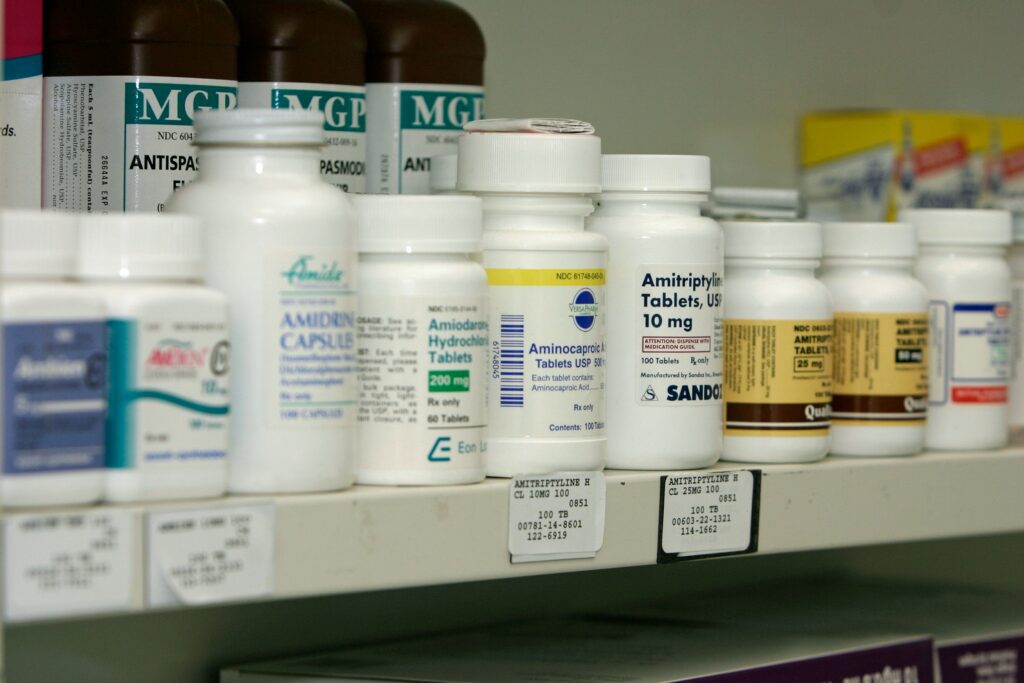 Prescription medication bottles lined up on a pharmacy shelf