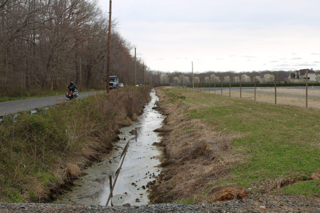 A drainage canal running through open land in Monroe Township, New Jersey, representing the natural resources residents are fighting to protect