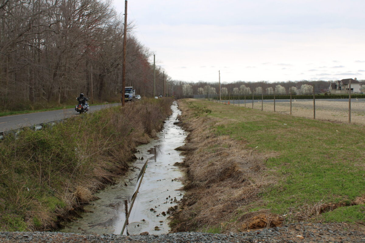 A drainage canal running through open land in Monroe Township, New Jersey, representing the natural resources residents are fighting to protect