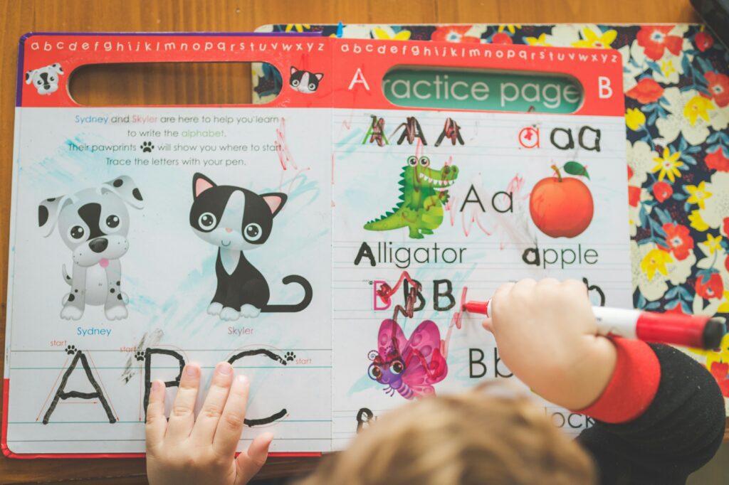 A young child tracing letters in an alphabet workbook at a preschool or early learning setting