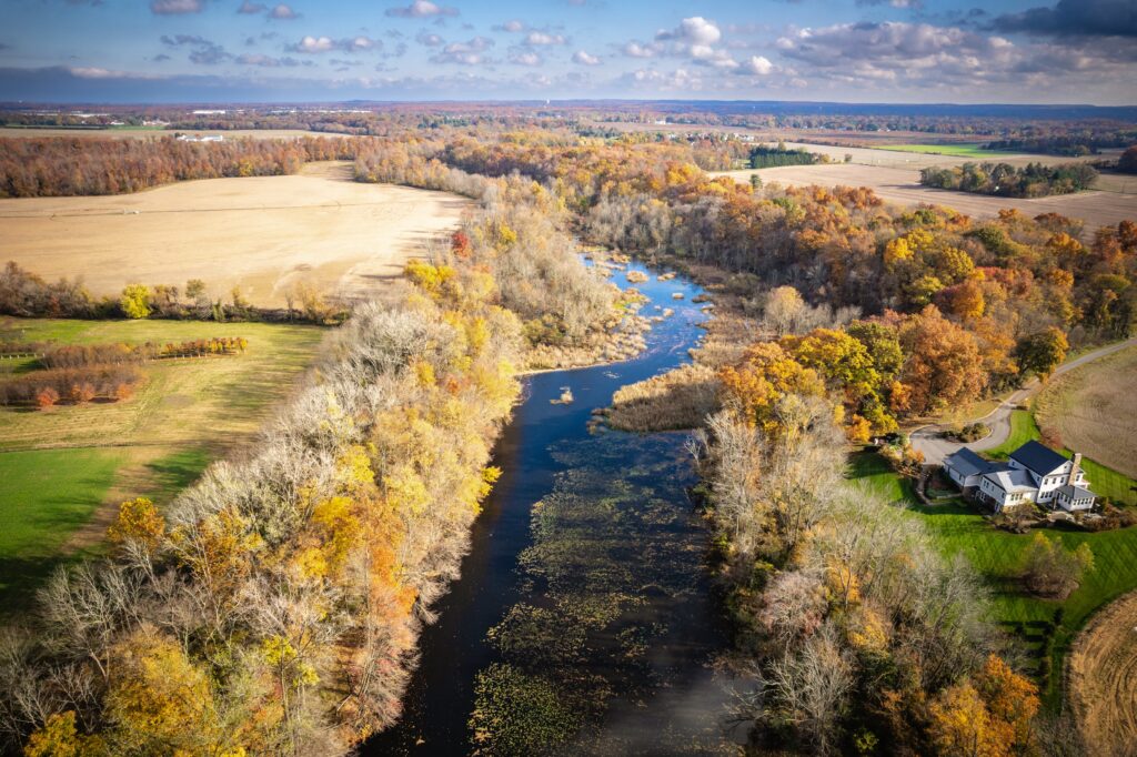 Aerial view of rural farmland and a river in New Jersey during fall foliage season