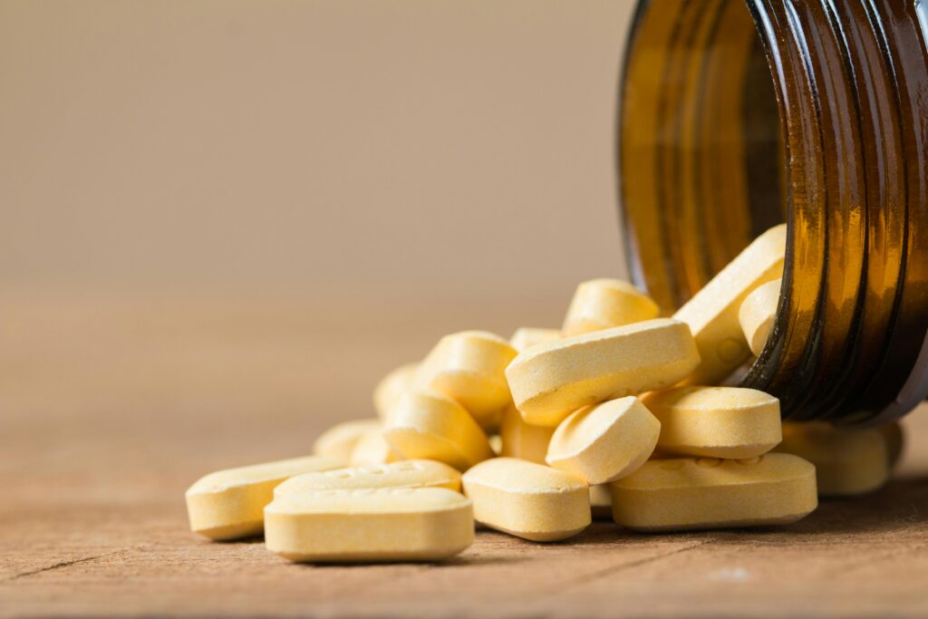 Vitamin tablets spilling out of an open bottle