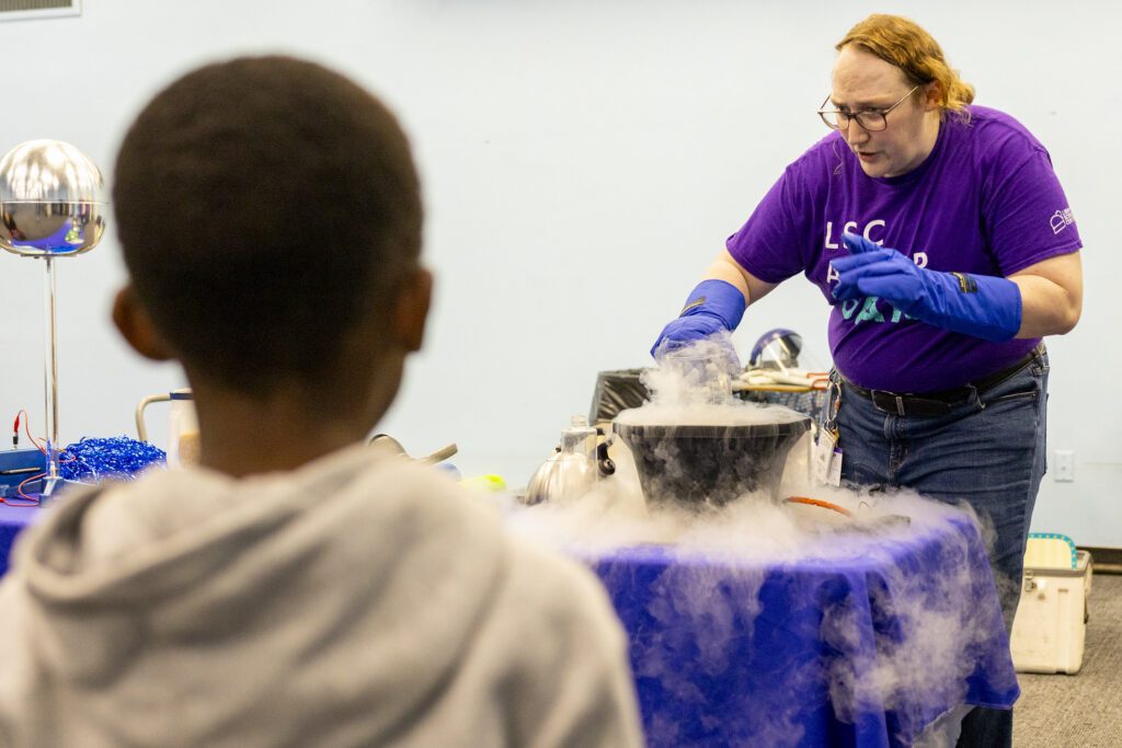 A science educator demonstrating a liquid nitrogen experiment for a child at STEAM Around the Square