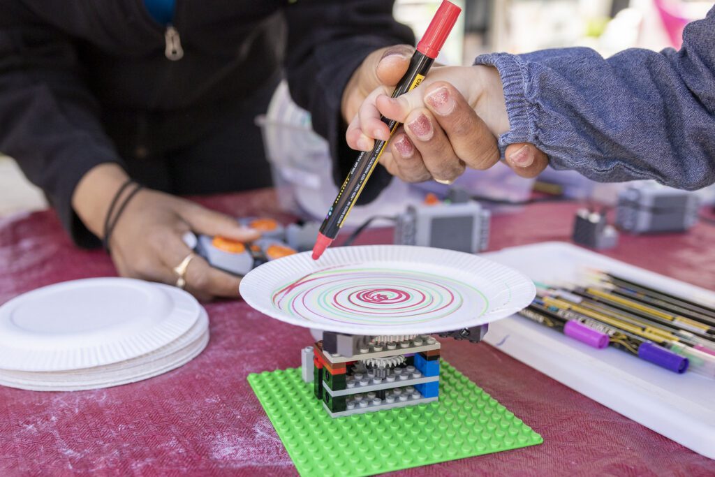 A child using a Lego-powered spin art machine at STEAM Around the Square in Newark, New Jersey