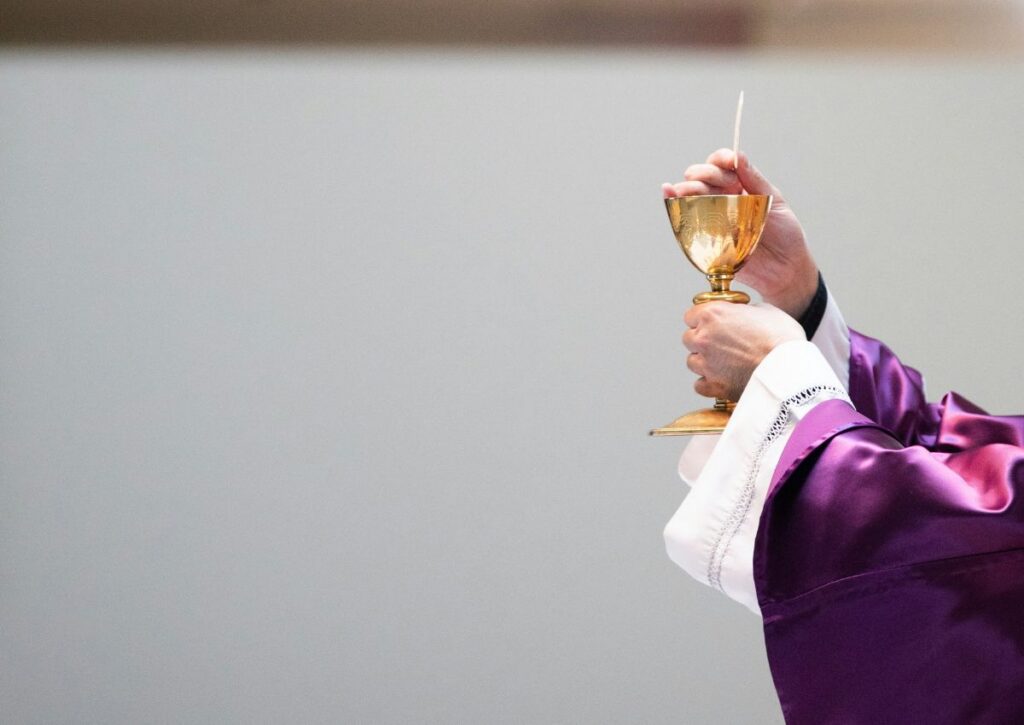 A Catholic priest holding a chalice during Mass at a Roman Catholic church in New Jersey