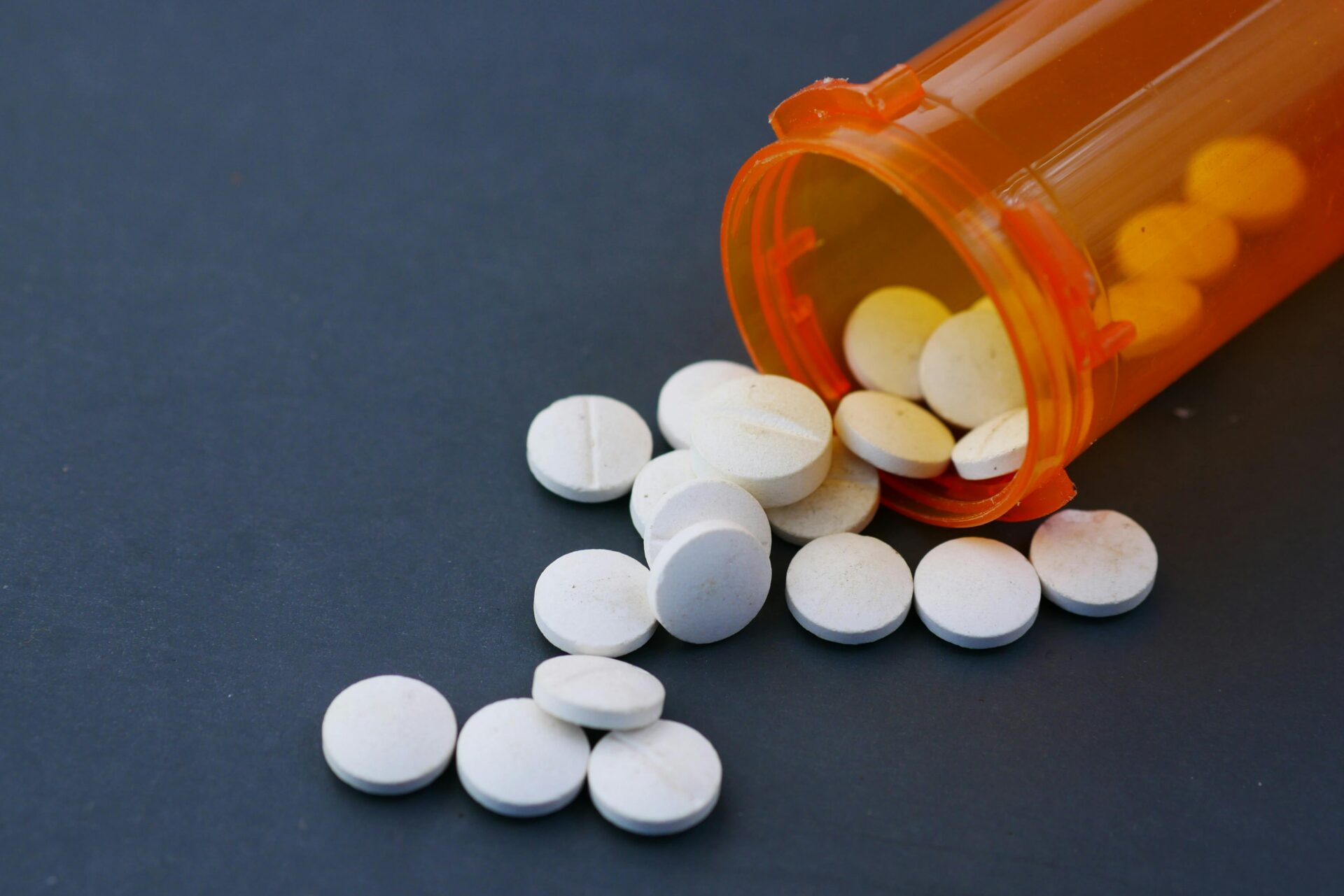 White prescription tablets spilling from an orange bottle representing a nationwide medication recall