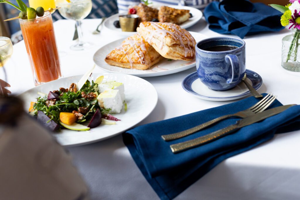 A brunch spread at 87 Sussex in Jersey City, New Jersey, featuring a bloody mary, glazed pastry, and beet salad