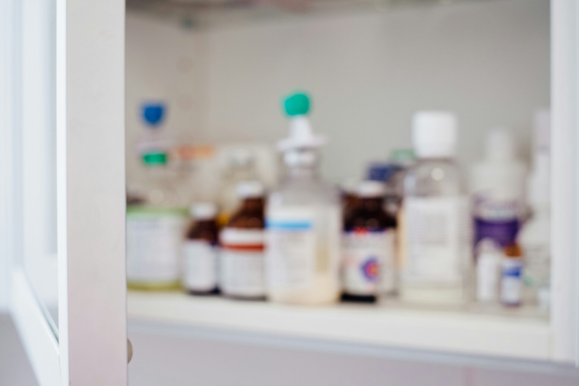 An open medicine cabinet stocked with prescription medication bottles