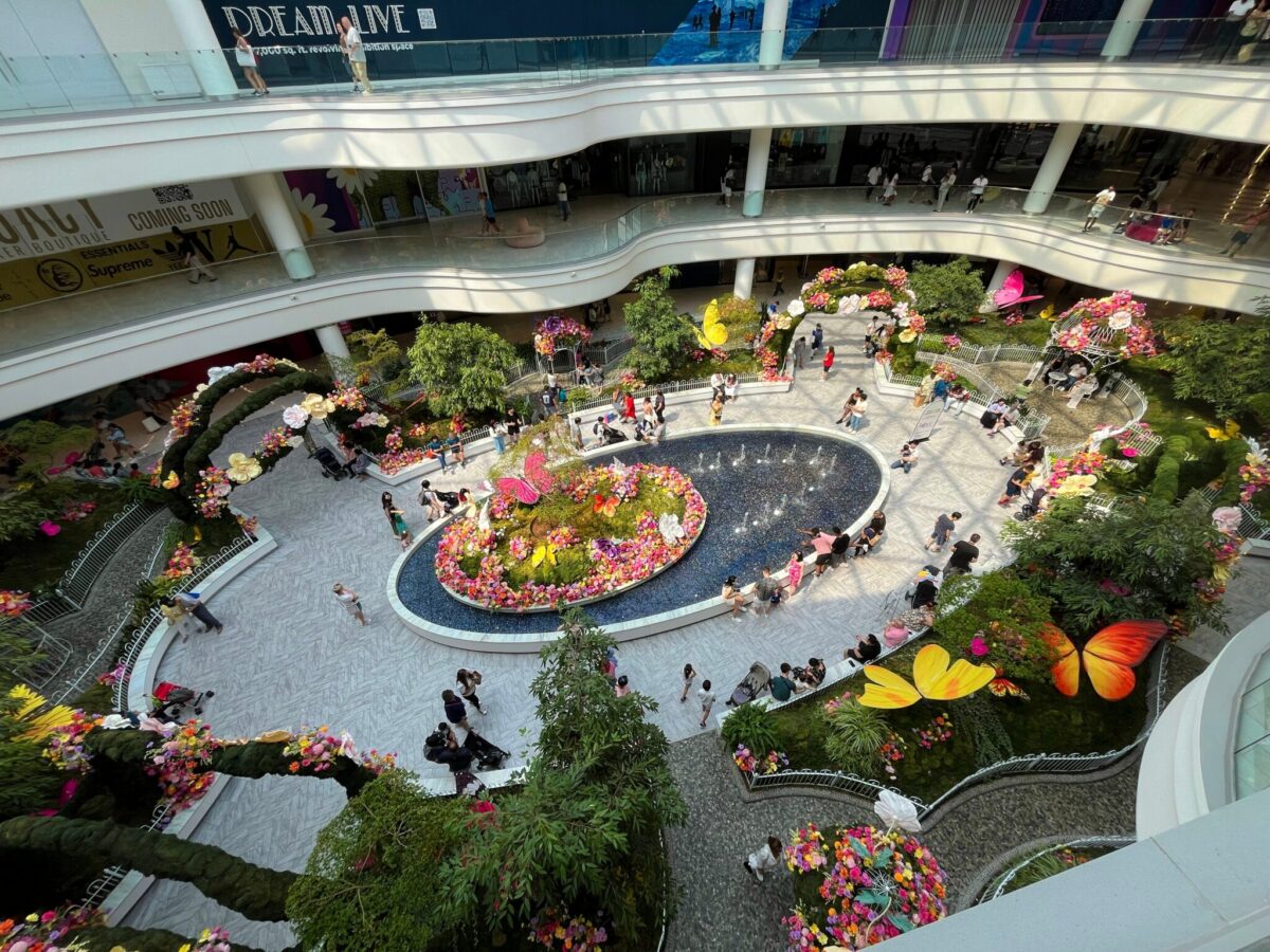 The interior atrium of American Dream Mall in East Rutherford, New Jersey, filled with shoppers and colorful floral displays.
