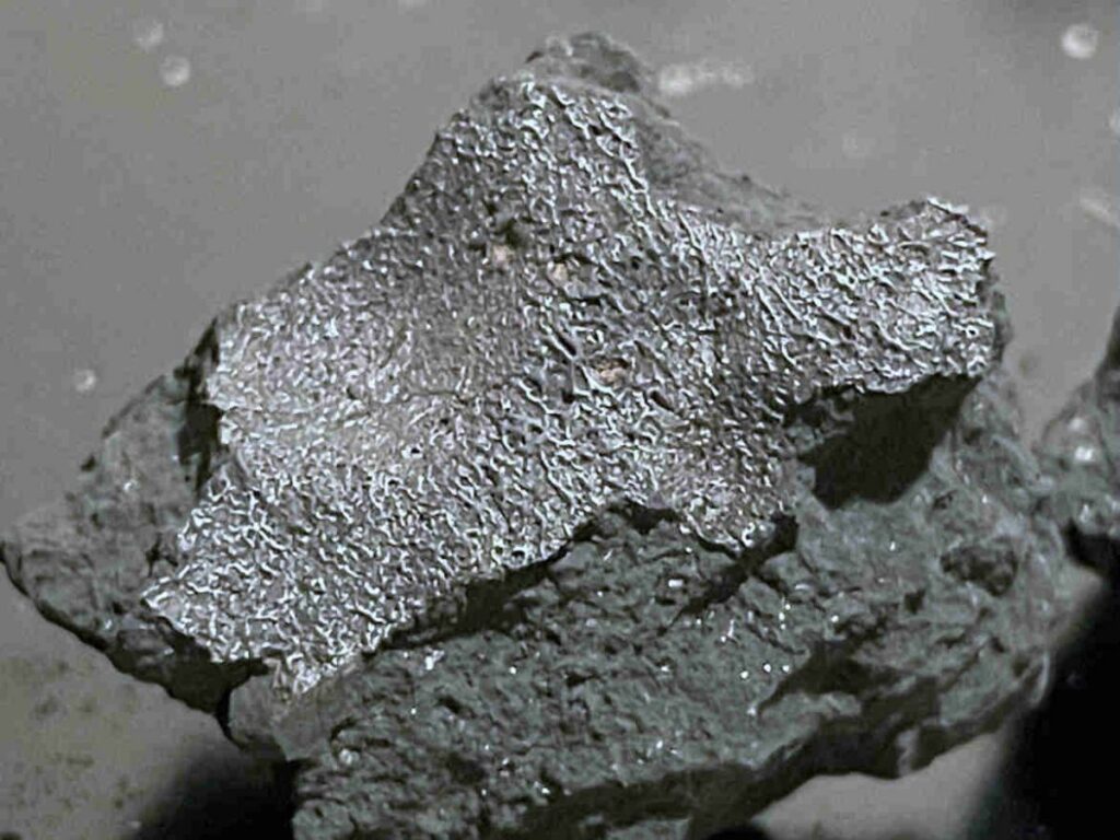 A fragment of the meteorite that crashed through a home's roof in Hillsborough, New Jersey, showing its gray, black, and silvery surface