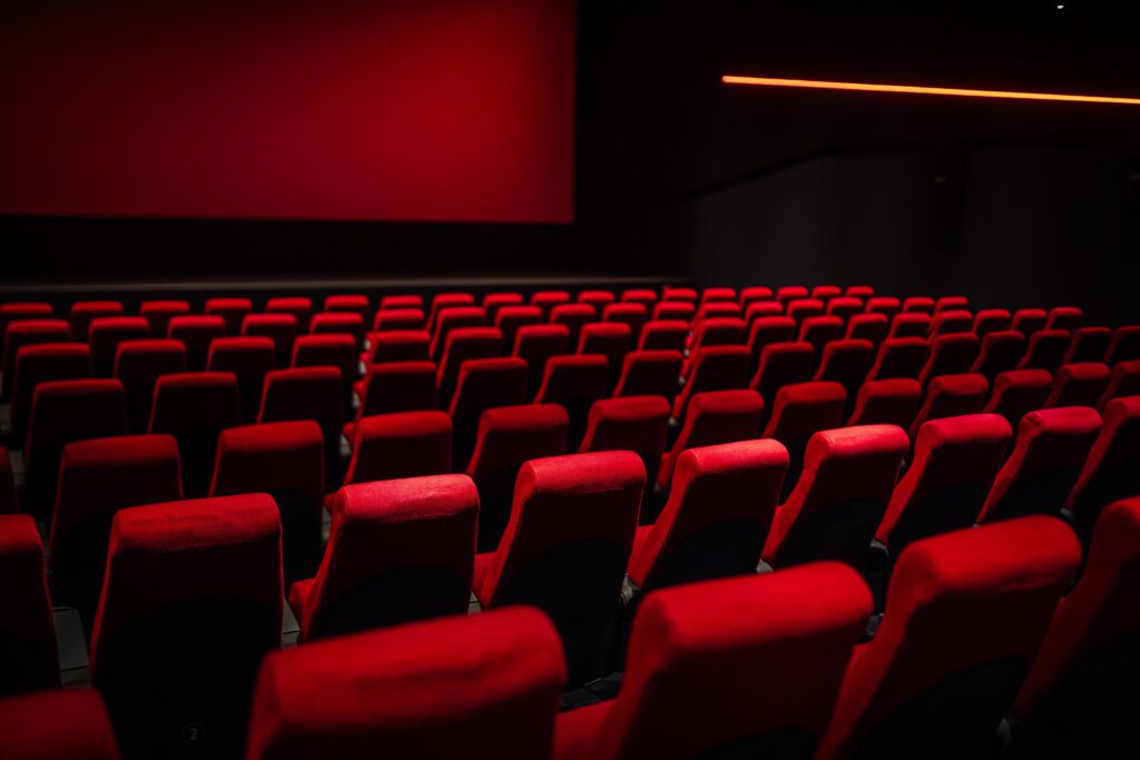 Rows of empty red seats in a movie theater.