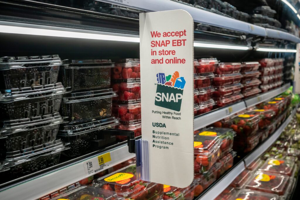 A sign reading "We accept SNAP EBT in store and online" displayed at a grocery store.