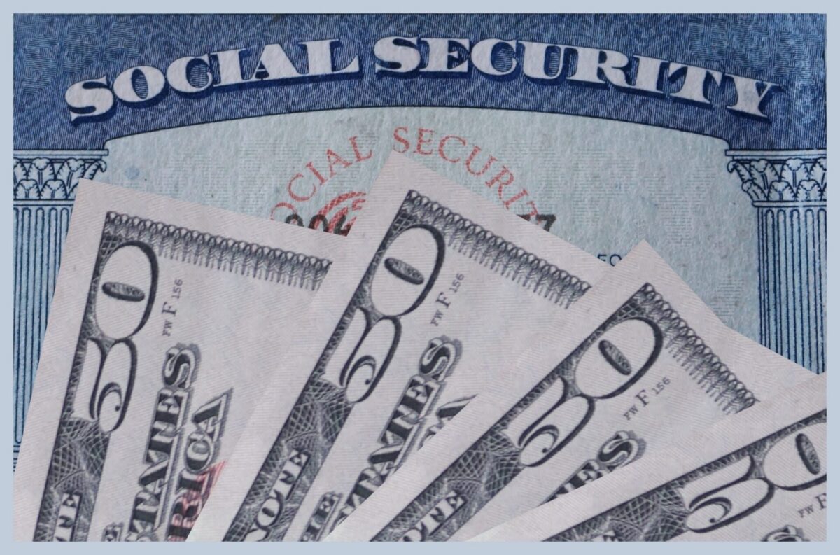 Social Security cards fanned out alongside U.S. currency, representing retirement benefit payments.