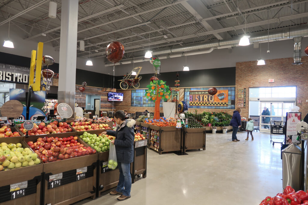 A shopper browsing a colorful produce display near the entrance of a grocery store
