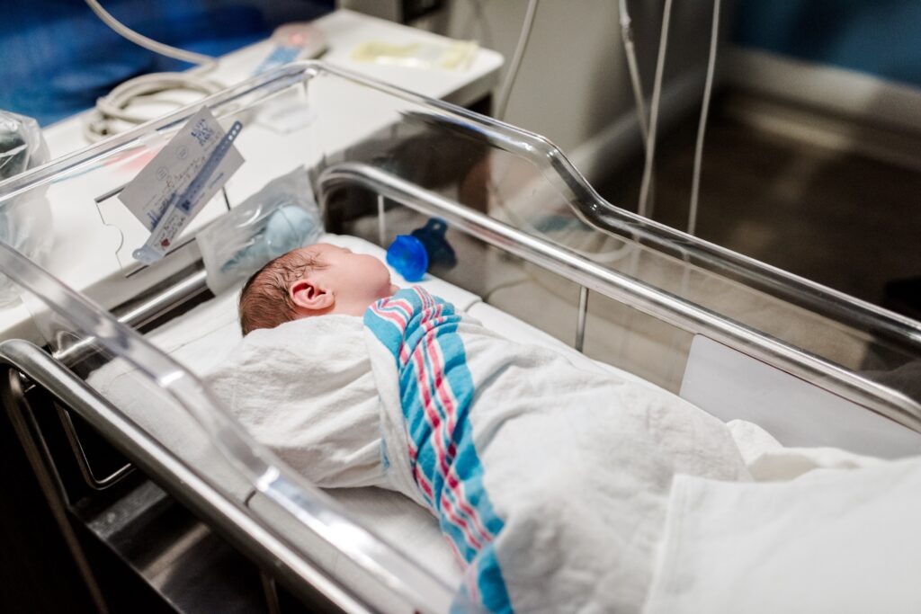 A newborn resting in a hospital bassinet, representing the maternity care offered at Inspira Medical Center Mullica Hill