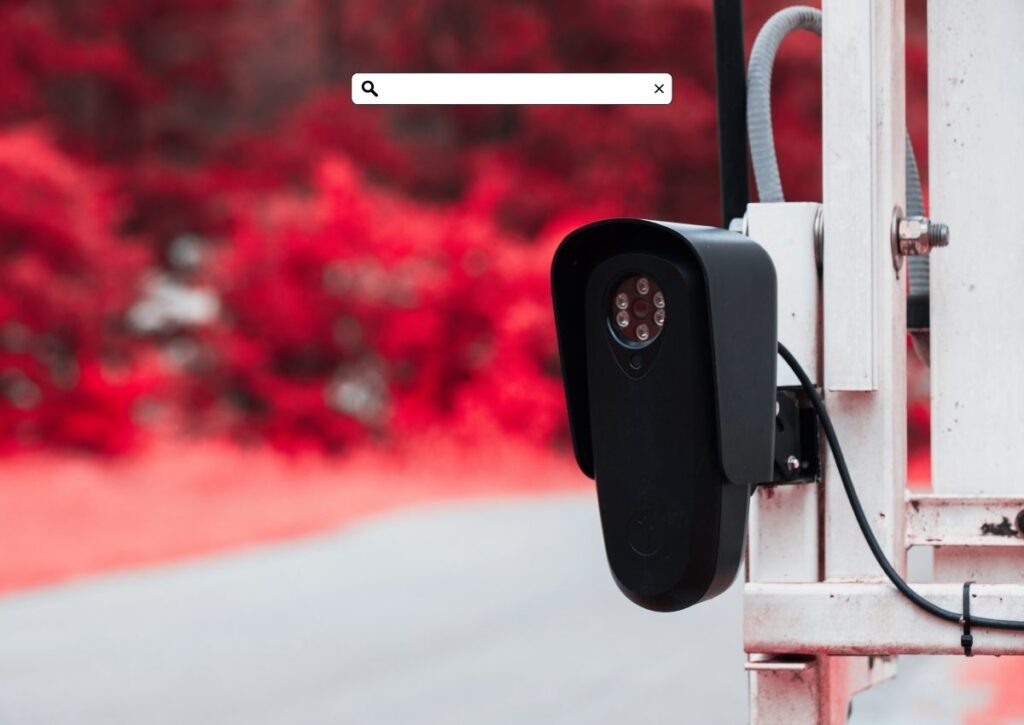 A red and black image of a Flock Safety camera with a search bar overlay, representing the new tool letting NJ drivers check if their license plate has been searched