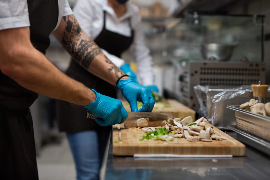 A chef's hands cutting vegetables in a restaurant kitchen