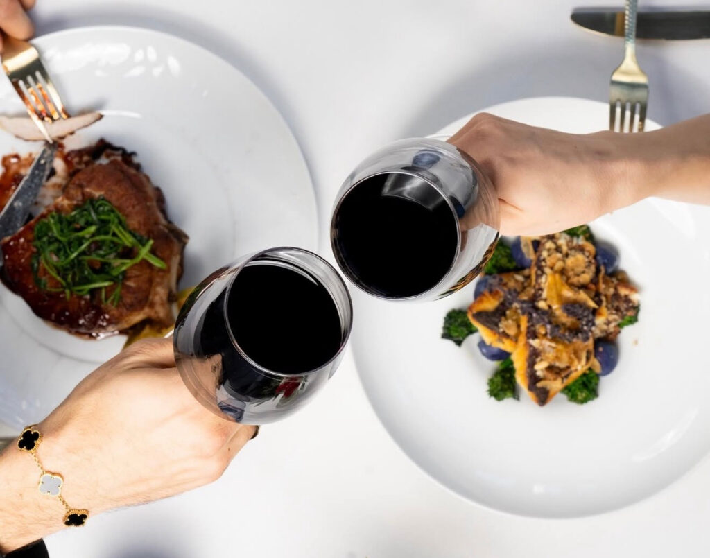 guests cheers two glasses of red wine at 87 Sussex in Jersey City, NJ