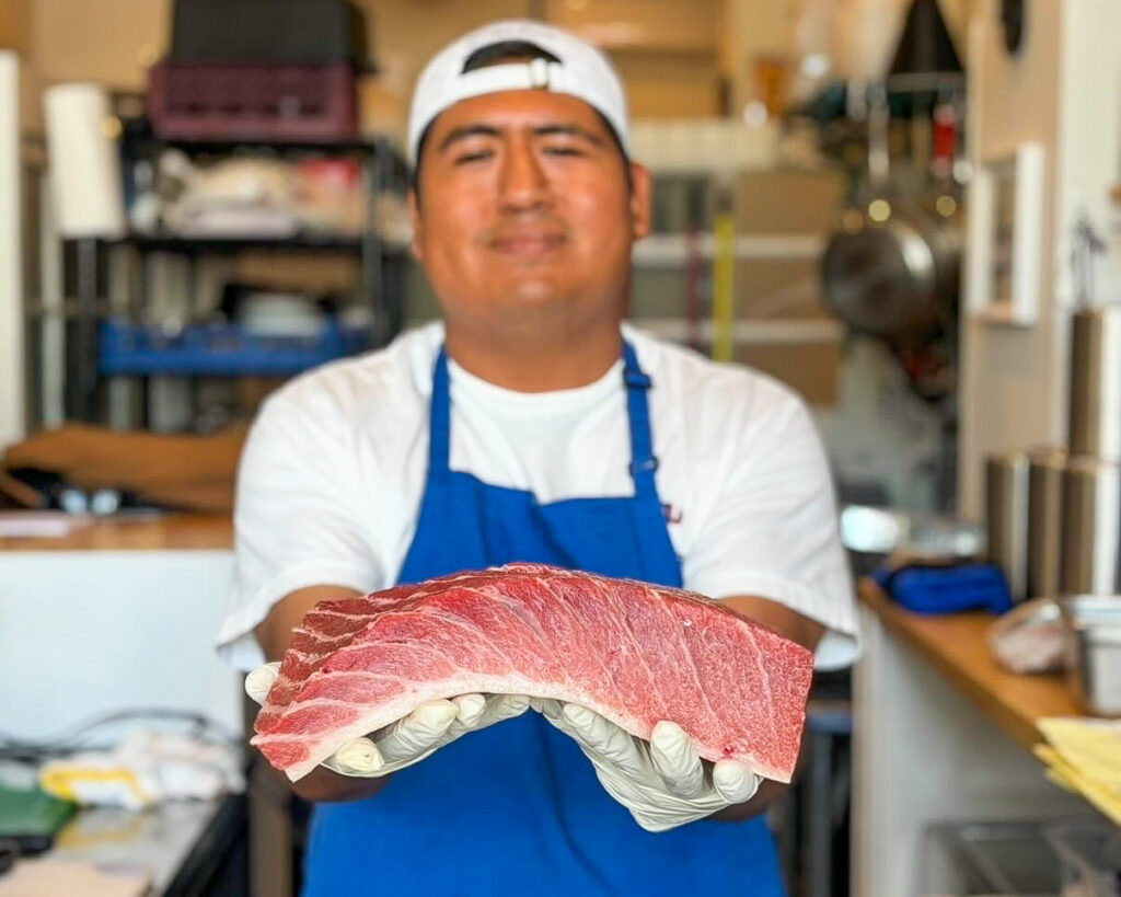 Chef Omar holds a fatty piece of tuna at Perla in Maplewood